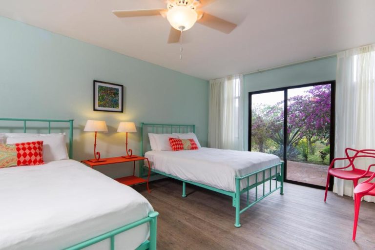 Habitación doble con camas gemelas de marco turquesa y vista al jardín en Villa San Ignacio