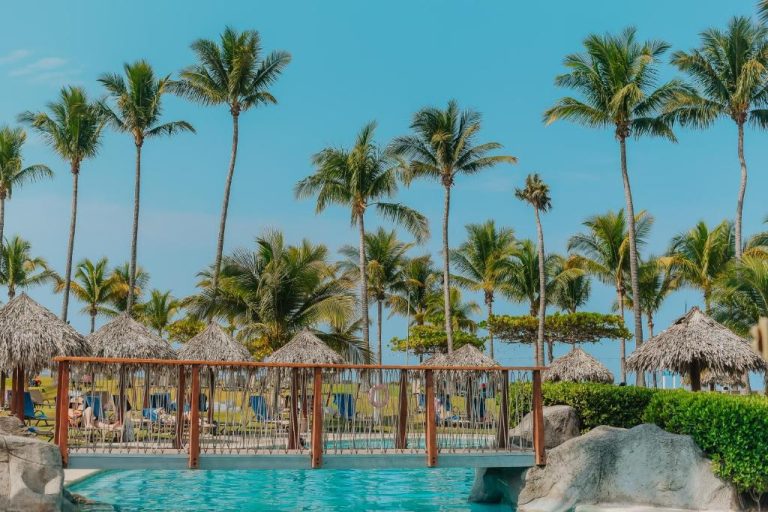 Piscina exterior con puente y palmas tropicales del Fiesta Resort All Inclusive en el Pacífico Central de Costa Rica