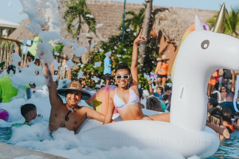 Pareja divirtiéndose en fiesta de espuma con flotador unicornio en la piscina del Fiesta Resort Costa Rica
