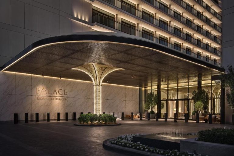 Entrada principal iluminada del Palace Dubai Creek Harbour con marquesina dorada y diseño árabe de lujo
