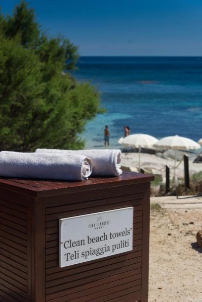 Servicio de toallas limpias en la playa del Hotel Cala Caterina con vistas al mar turquesa de Cerdeña