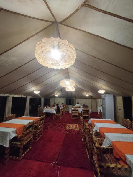 Salón comedor elegante bajo carpa del Velaria Luxury Camp con mesas y lámparas decorativas