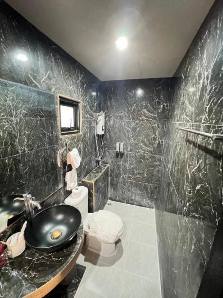 Baño de mármol negro con lavabo redondo y ducha en Coco Residence Si Saket