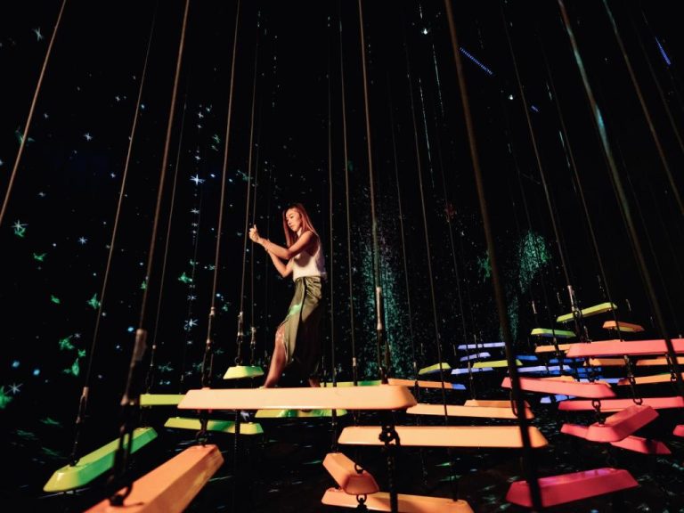 Mujer entre columpios de colores neón en instalación artística interactiva del Marina Bay Sands