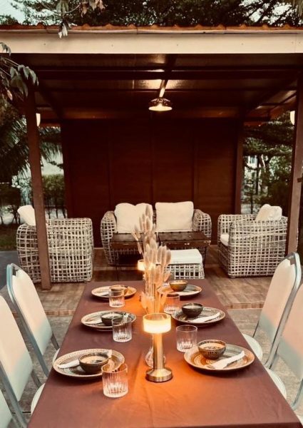 Mesa de cena romántica con velas en terraza exterior del Coco Residence Si Saket con gazebo