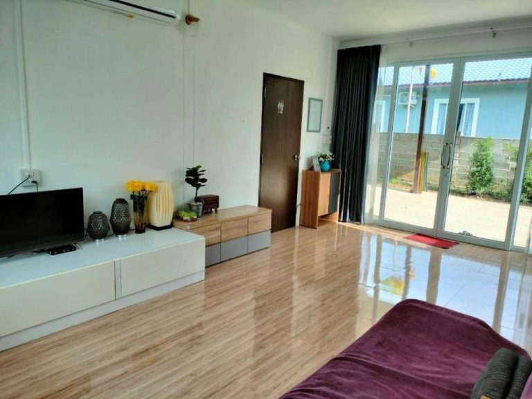 Salón luminoso con televisor y suelos de madera en Coco Residence Si Saket con acceso a terraza exterior