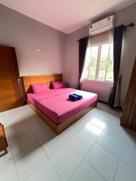 Habitación doble con cama matrimonial rosa y aire acondicionado en Coco Residence Si Saket