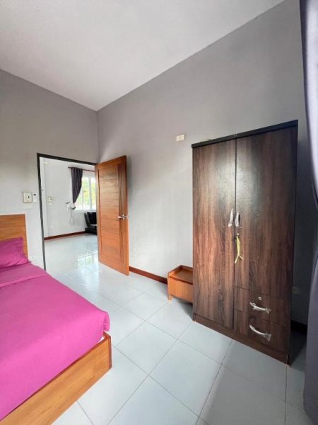 Habitación con cama doble rosa y armario de madera en Coco Residence Si Saket