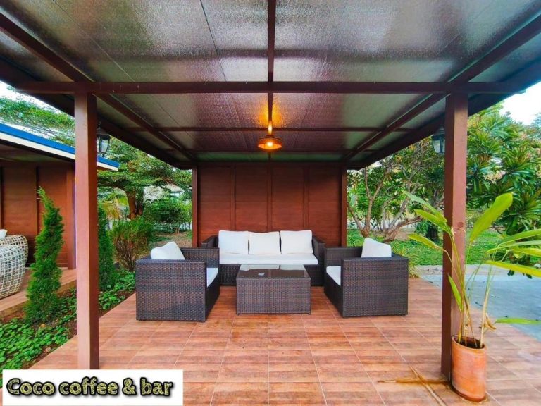 Terraza cubierta con sofás de ratán y mesa de centro en Coco Residence Si Saket, área de descanso al aire libre