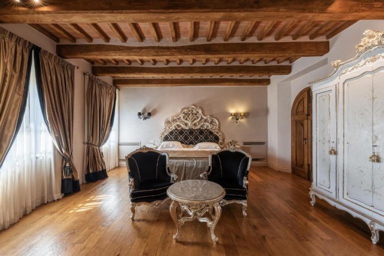 Habitación de lujo estilo barroco con cama tallada y techo de vigas en Relais La Corte dei Papi