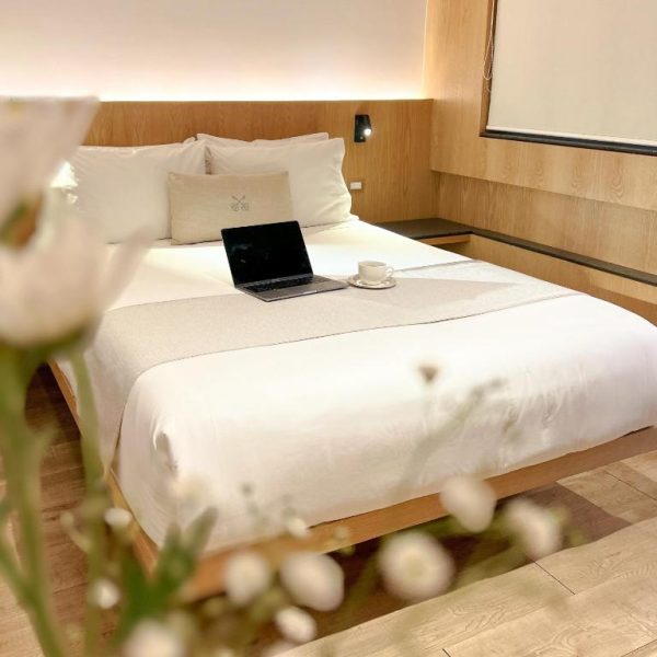 Habitación doble minimalista con cama king size, laptop y taza de café en Reforma Guest House
