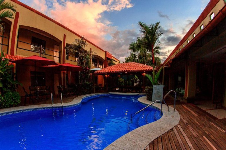Piscina exterior con palmeras y gazebo del Hotel Boutique Iguana Verde al atardecer