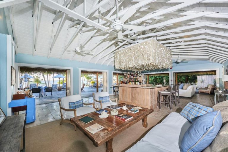 Salón bar interior con techo de vigas blancas y lámpara de conchas del Tiamo Resort en Bahamas