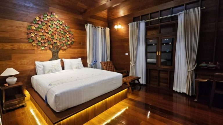 Habitación de madera con cama iluminada y decoración árbol en DooNa Resort แลภูดูนา
