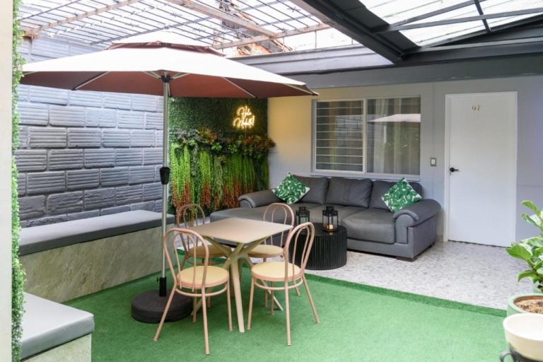 Terraza exterior con mesa, sillas y sofá del Hotel Hola Medellín con jardín vertical decorativo