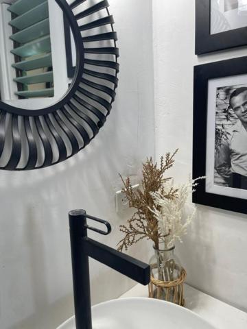 Baño moderno del Catcha Falling Star con lavabo blanco, grifo negro mate y espejo decorativo redondo