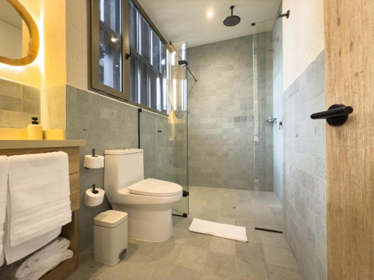 Baño moderno con ducha de lluvia y acabados en piedra natural del Moabi Hotel