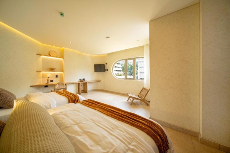 Habitación doble con diseño moderno y ventana ovalada en Moabi Hotel