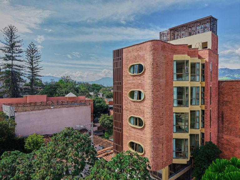 Fachada exterior del Moabi Hotel con arquitectura de ladrillo rojo y ventanas ovaladas en Medellín