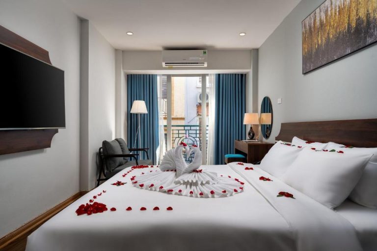 Habitación romántica con cisnes de toalla y pétalos de rosa en Astoria Hotel Hanoi