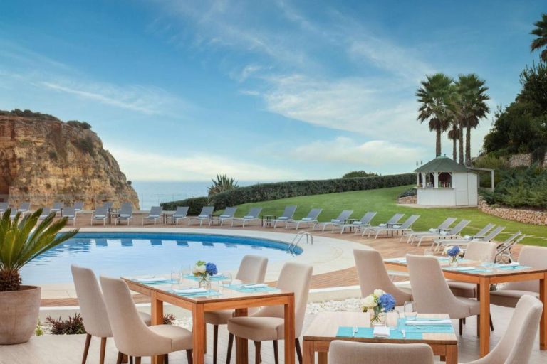Terraza restaurante con piscina exterior y vistas al mar en el Hotel Tivoli Carvoeiro, Algarve