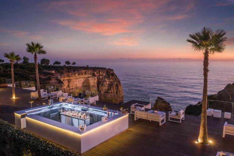 Bar terraza exterior del Tivoli Carvoeiro con vistas al mar y acantilados al atardecer