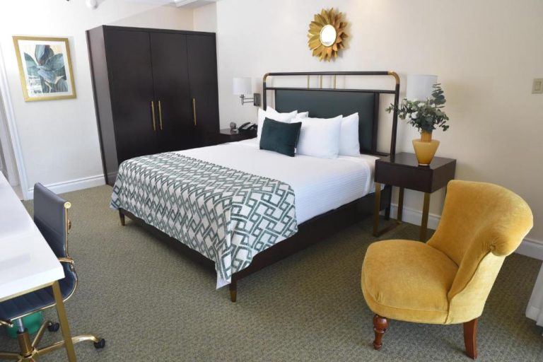 Habitación king con cabecero verde y silla dorada en Courtleigh Hotel & Suites Jamaica