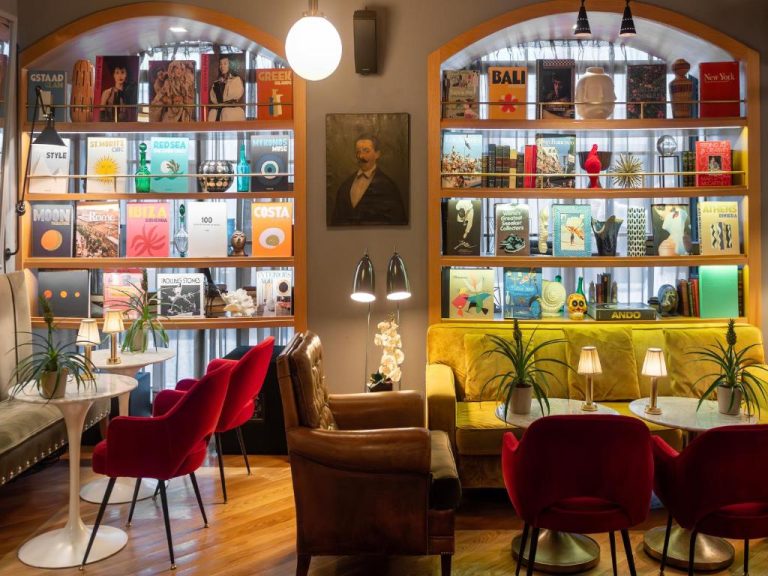 Zona de lounge con biblioteca de viajes y sofás coloridos en Browns Central Hotel Lisboa