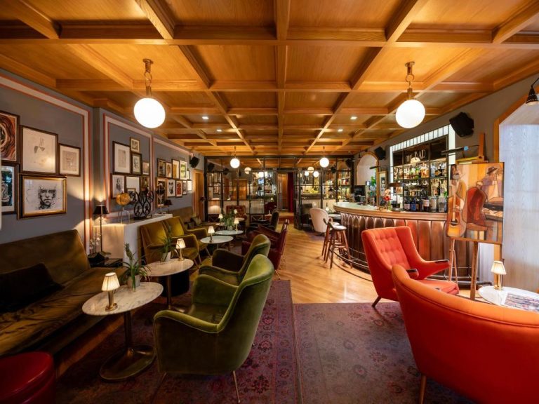 Bar y salón lounge con sillones de terciopelo verde y rojo en Browns Central Hotel