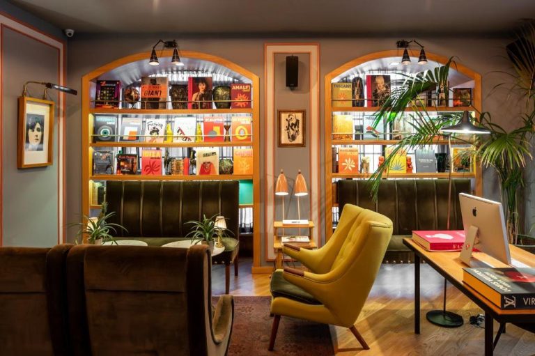 Zona lounge con biblioteca y sillones retro en el Browns Central Hotel, decoración vintage con estanterías iluminadas