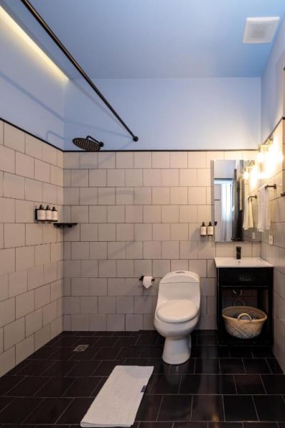 Baño moderno con ducha de lluvia y azulejos blancos en HAB Hotel Bogotá