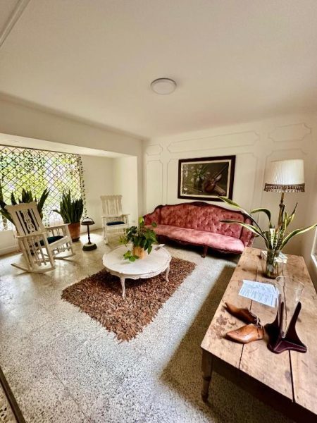 Sala de estar vintage con sofá rosa y decoración clásica del Hotel Boutique Fiorentina Medellín