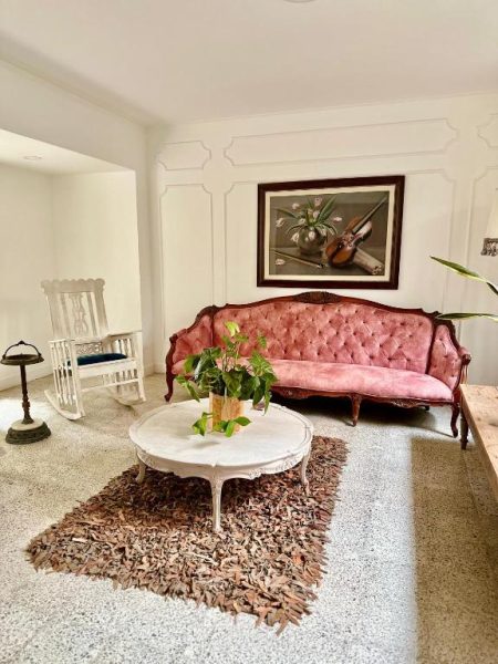 Sala vintage con sofá rosa tufteado y decoración clásica en Hotel Boutique Fiorentina Medellín