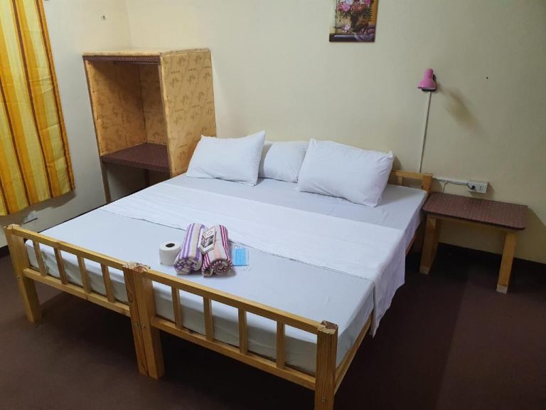 Habitación doble con cama de madera y ropa blanca en Cool Martin Family Hotel and Resort