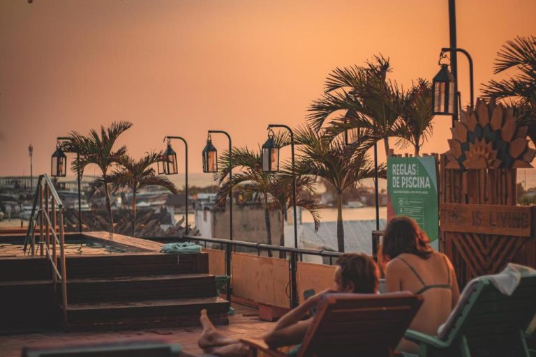 Terraza con piscina y palmeras del Hotel Kim al atardecer con tumbonas y lámparas decorativas