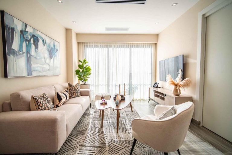 Salón moderno con sofá beige y televisor en las suites del Aston Rubi City Suites