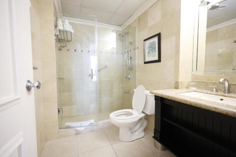 Baño moderno con ducha de cristal, inodoro y lavabo con encimera de mármol en Courtleigh Hotel & Suites