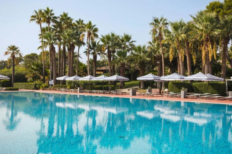 Piscina exterior con tumbonas y palmeras en Mangia's Brucoli Sicily Autograph Collection