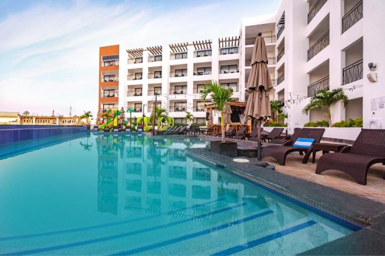 Piscina exterior con tumbonas y sombrillas del Medano Hotel and Spa con vistas al edificio principal