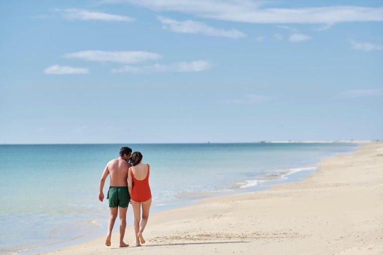 Pareja paseando por la playa del Iberostar Waves Averroes con aguas turquesas y arena blanca