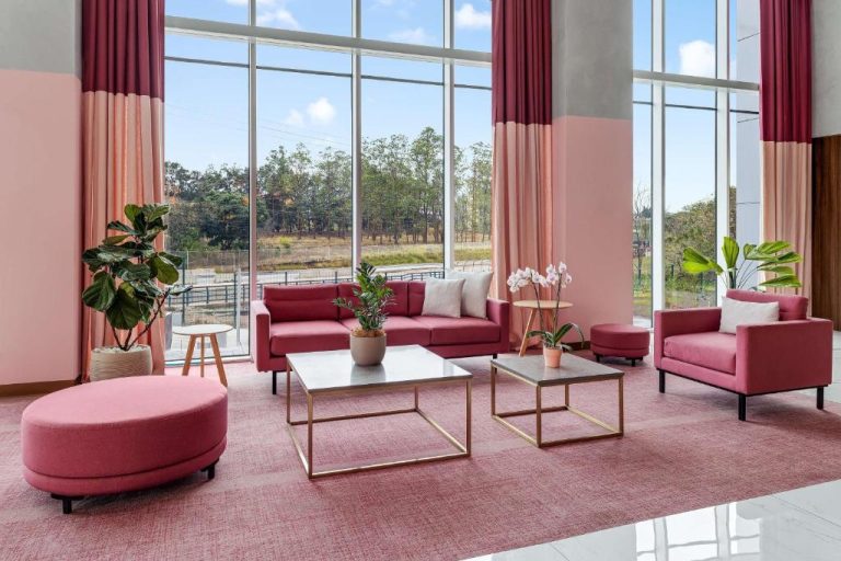 Elegante lobby con sofás rosas y grandes ventanales del Hilton Garden Inn San Jose Airport City Mall