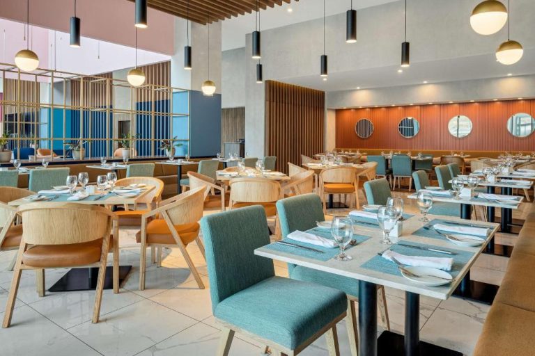 Restaurante interior elegante del Hilton Garden Inn San José Airport con mesas y sillas modernas