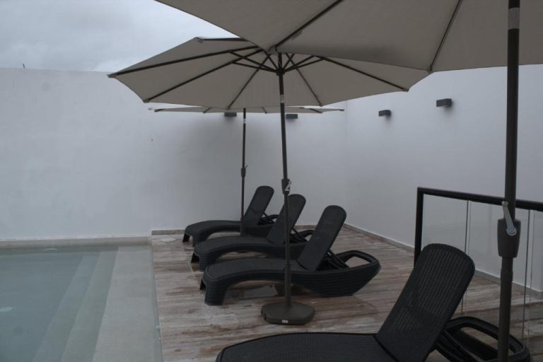 Terraza con tumbonas y sombrilla junto a la piscina del Hotel B10 Distinctive Hotel
