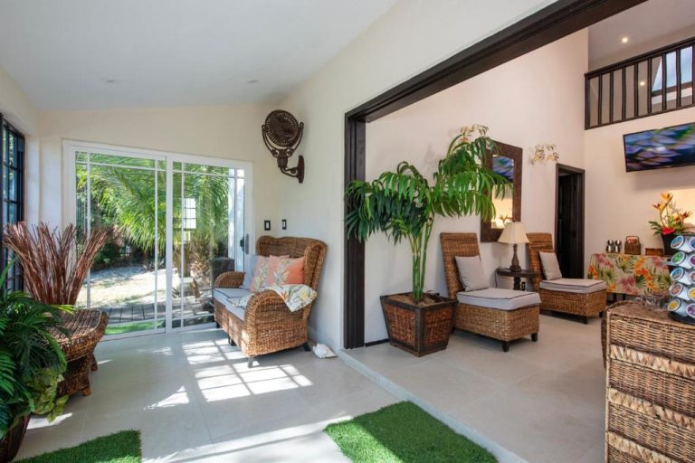 Sala de estar tropical con muebles de mimbre y plantas en The Pilot House