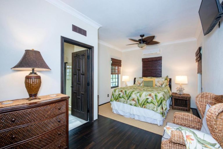 Habitación tropical con cama matrimonial, ventilador de techo y sillones de mimbre en The Pilot House