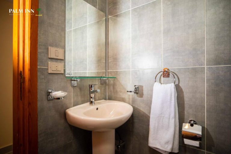 Baño moderno con lavabo, espejo y toallas blancas en el Palm Inn Hotel Hurghada, Egipto