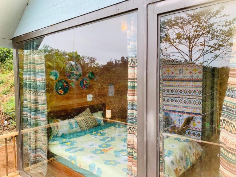 Habitación con paredes de cristal y cama doble rodeada de naturaleza en MANG DEN Romantic
