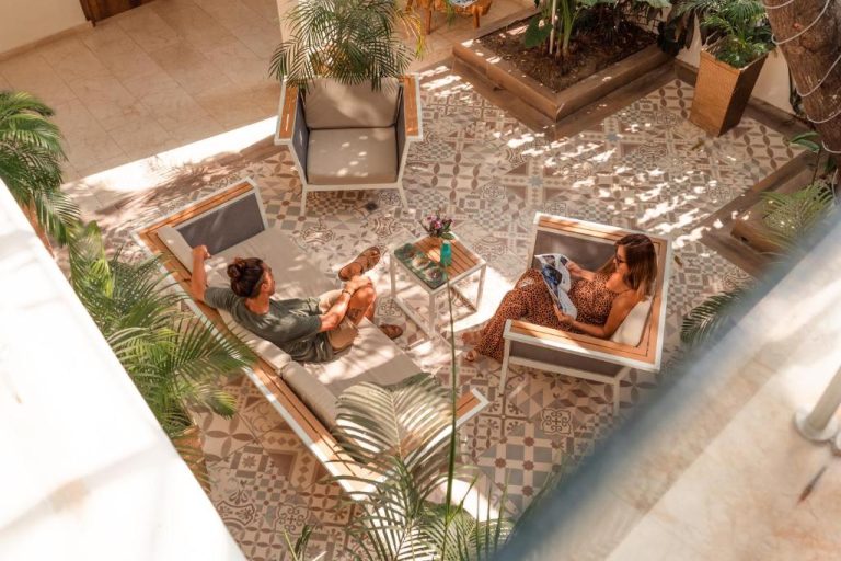 Pareja relajándose en tumbonas del patio interior del Cartagena Royal Hotel Boutique rodeado de palmeras