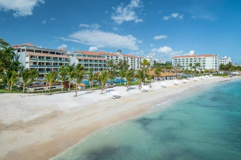 Vista aérea de la playa privada con tumbonas y palmeras del Sandals Dunns River en Jamaica