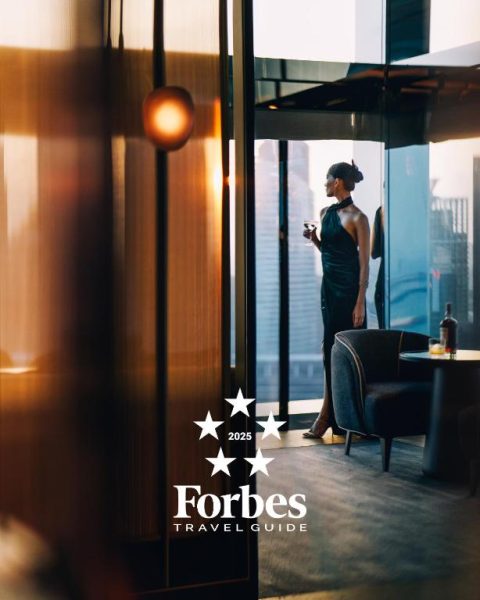 Mujer elegante con copa de vino disfrutando de las vistas panorámicas en el bar lounge del Marina Bay Sands